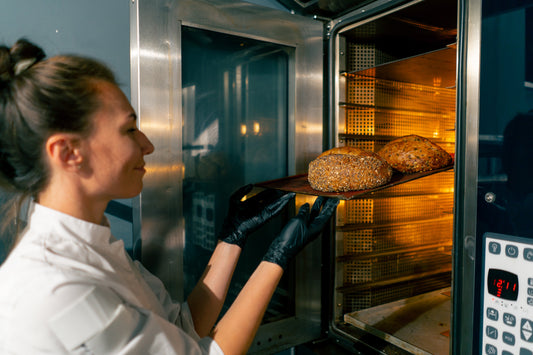 Chef inserisce pane artigianale in forno professionale ventilato, dettaglio interno cucina ristorante, scelta attrezzatura
