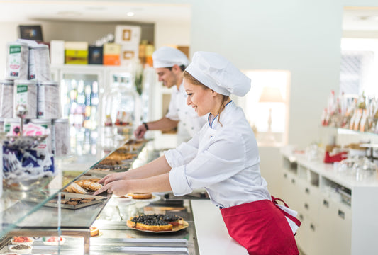 Gelataia al banco di una gelateria artigianale prepara dolci e gelati, ambiente moderno, esempio di attività commerciale
